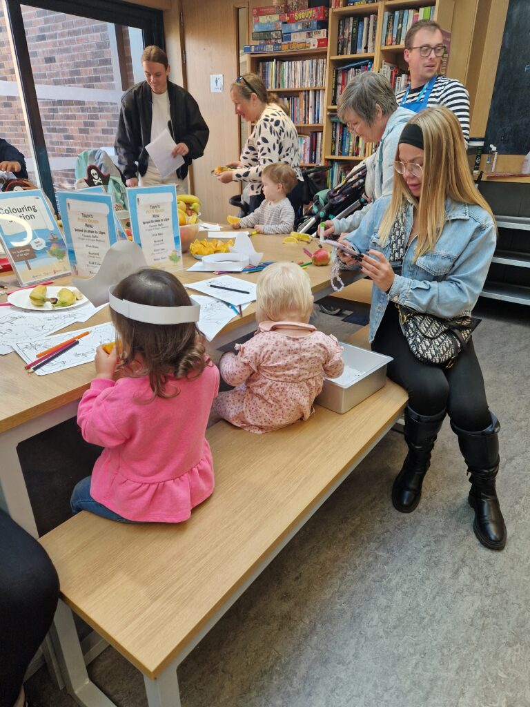 A group of young children and their parents/carers enjoying the craft activities at our Pirate Brunch Community Meal.