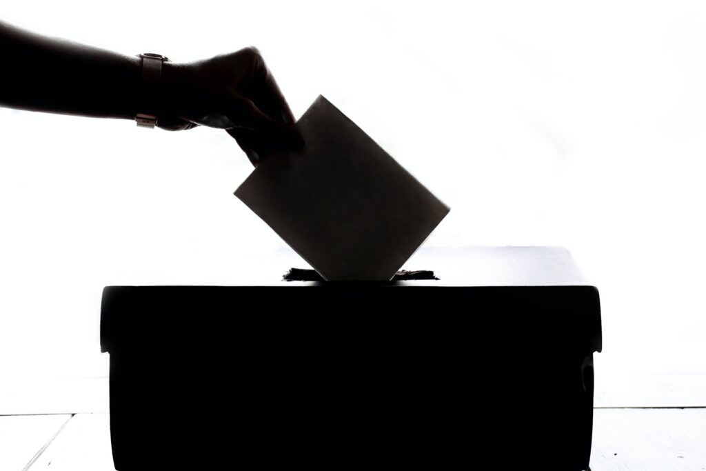 Silhouette photo of person placing a rectangular piece of paper into a box